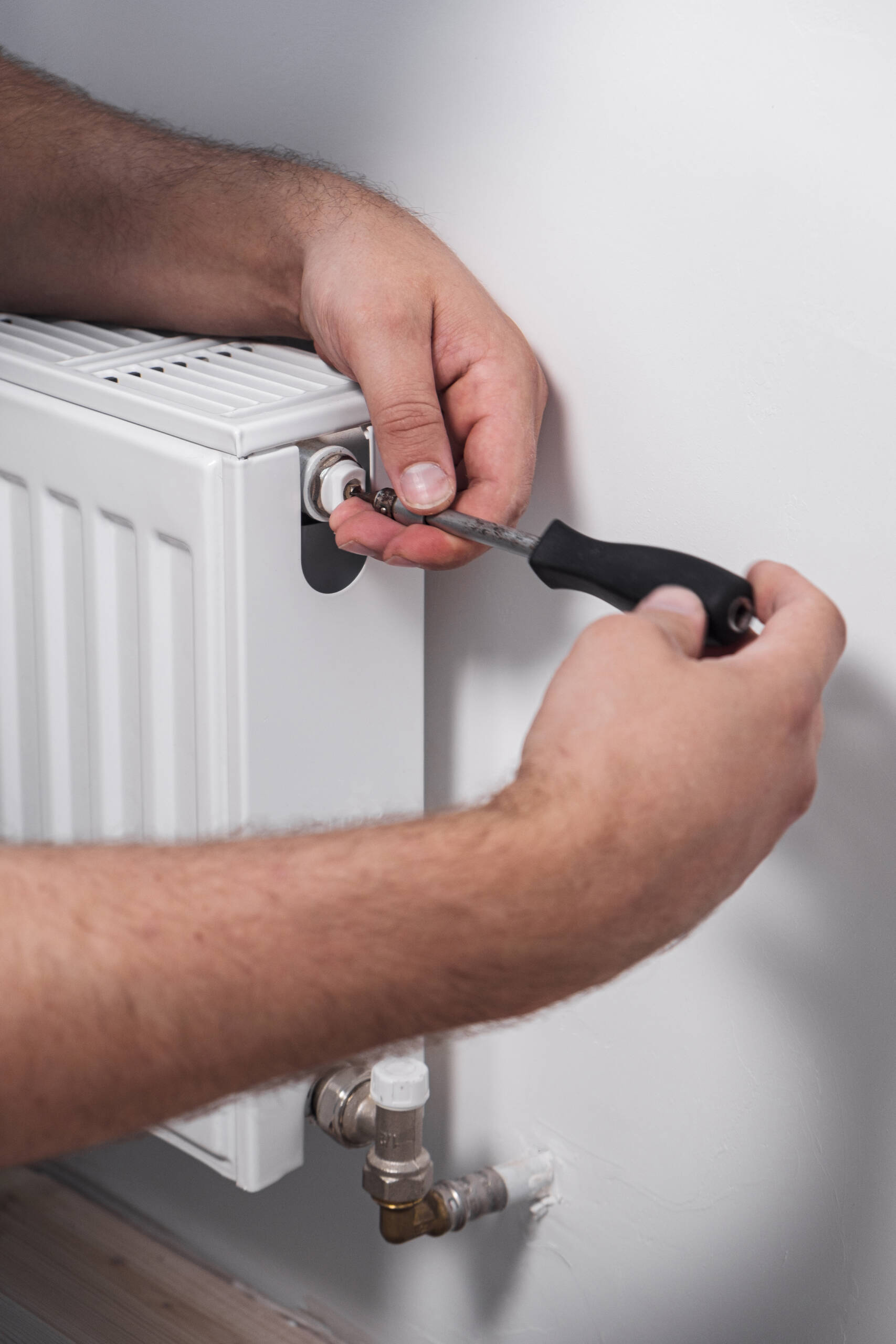 Plumber installing new steel hot water central heating radiator